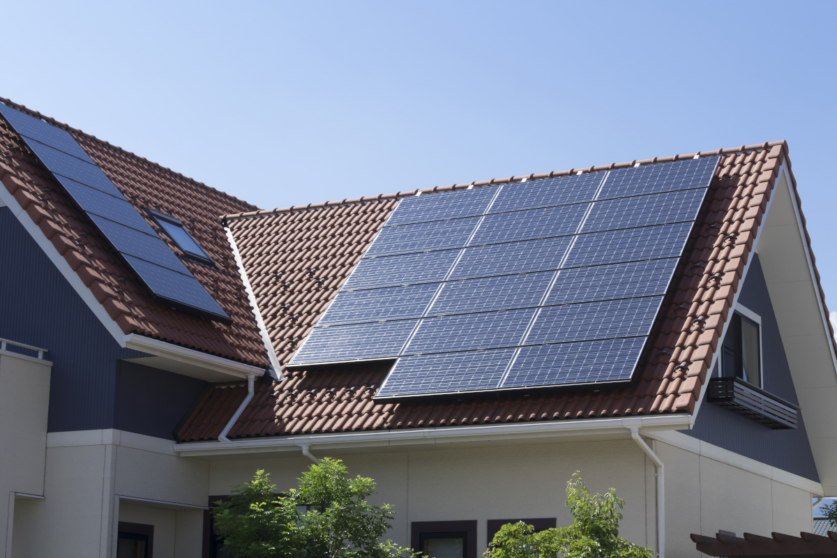 Wohnhaus mit Solaranlagen auf Ziegeldach unter blauem Himmel
