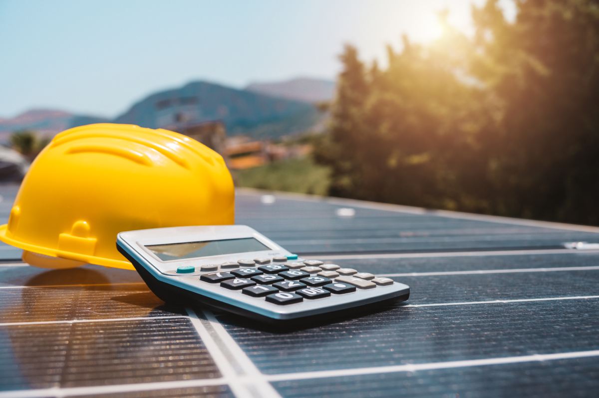Solarpanel mit Bauhelm und Taschenrechner im Sonnenlicht
